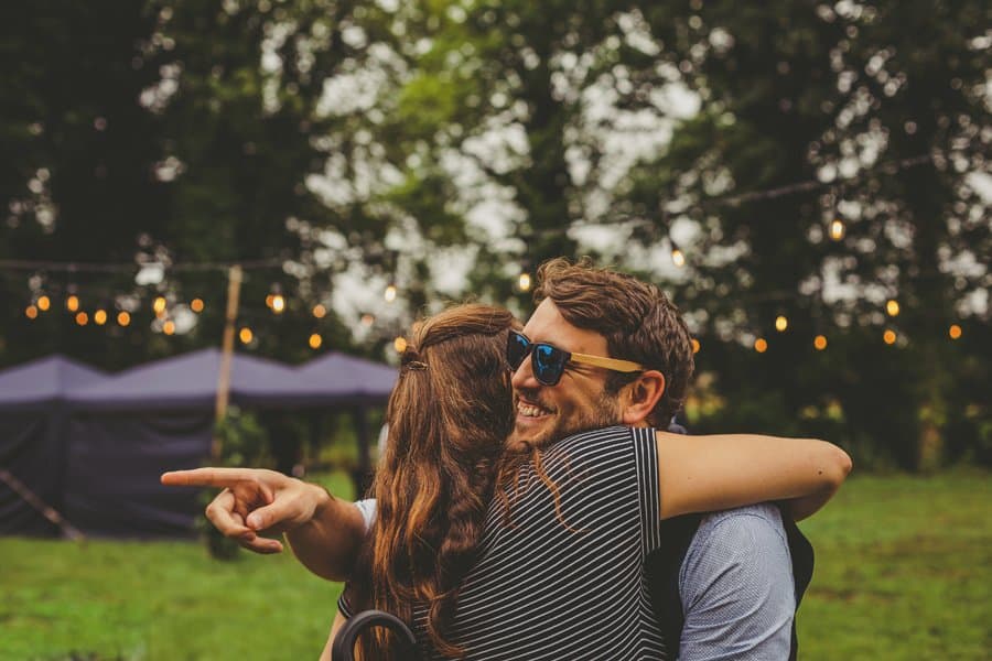 A wedding guest points to someone as he hugs a friend