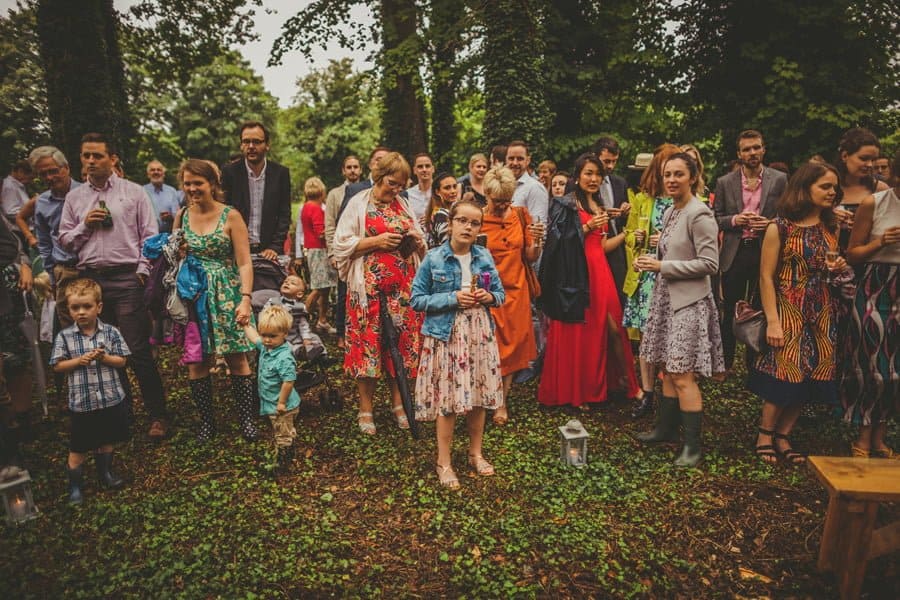 A girl stands in front of the line of wedding guests