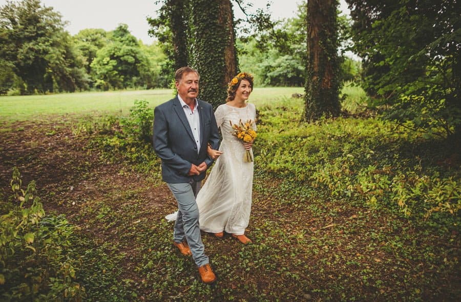 The bride and her father walk into the woods