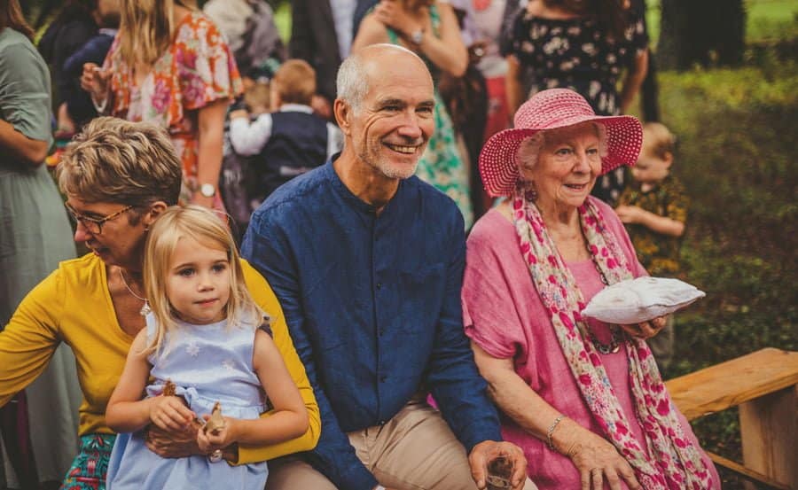 The grooms father and the grooms grandmother sit and listen to the ceremony