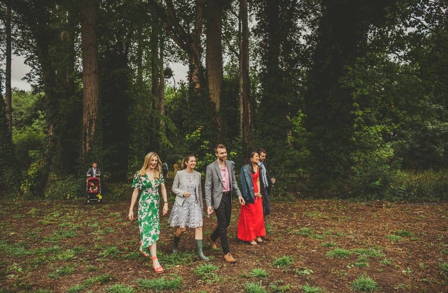Wedding guests walk out of the woods after the outdoor wedding ceremony