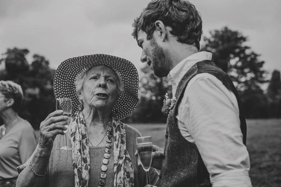 The groom and his grandmother sip champagne and talk to each other
