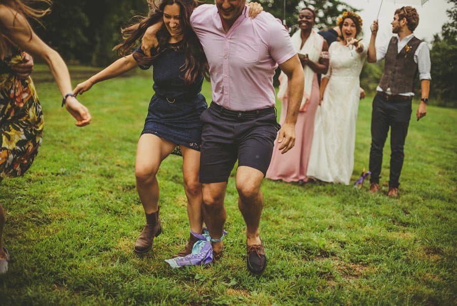 A couple running across the field with a scarf tied between their ankles