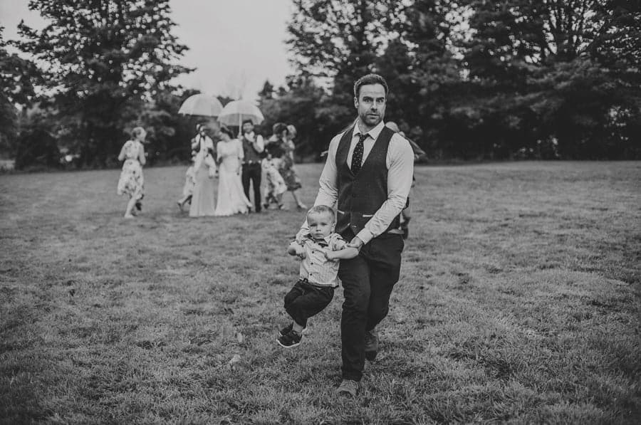 A wedding guest runs across the field with his son