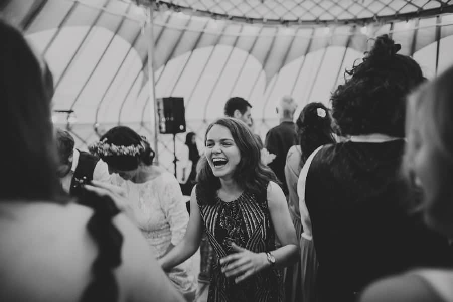 A wedding guest laughs with friends on the dance floor in the yurt