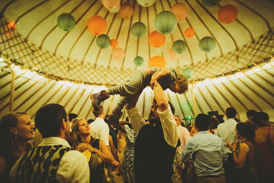 A wedding guest lifts his son in the air on the dancefloor