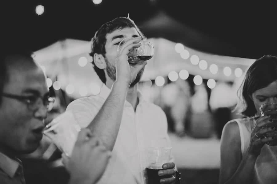 The groom drinks a shot of whisky outside the yurt