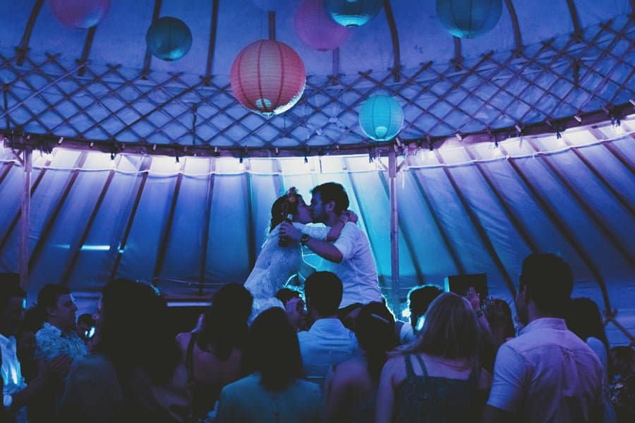 The bride and groom are lifted in the air and embrace each other on the dance floor