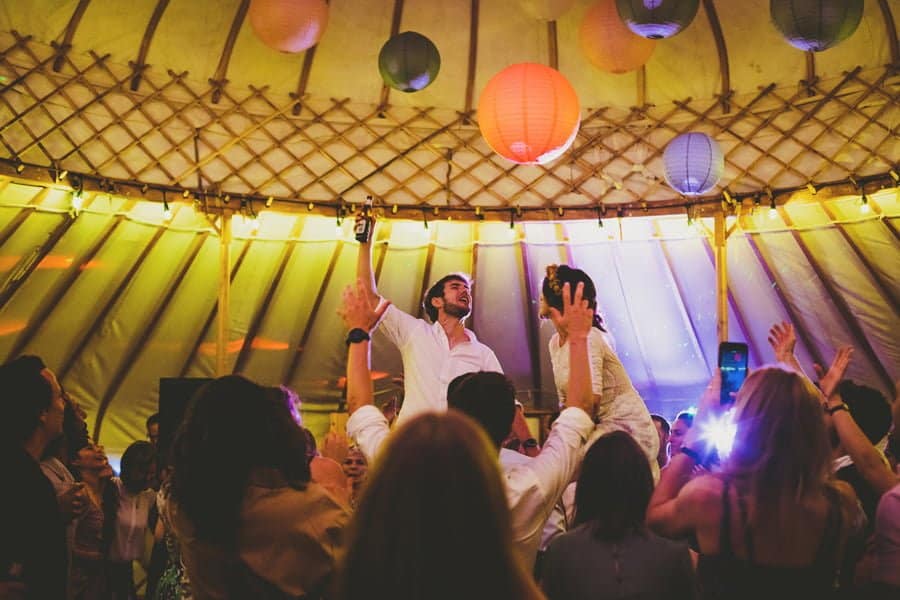 The groom raises his arm in the air and celebrates the end of his wedding day on the dance floor