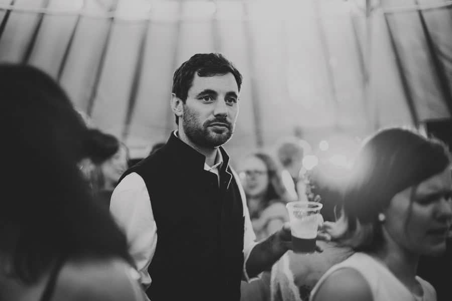 A wedding guest holds a glass of beer in the yurt
