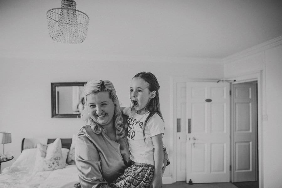A bridesmaid lifts up a flower girl and they both start laughing