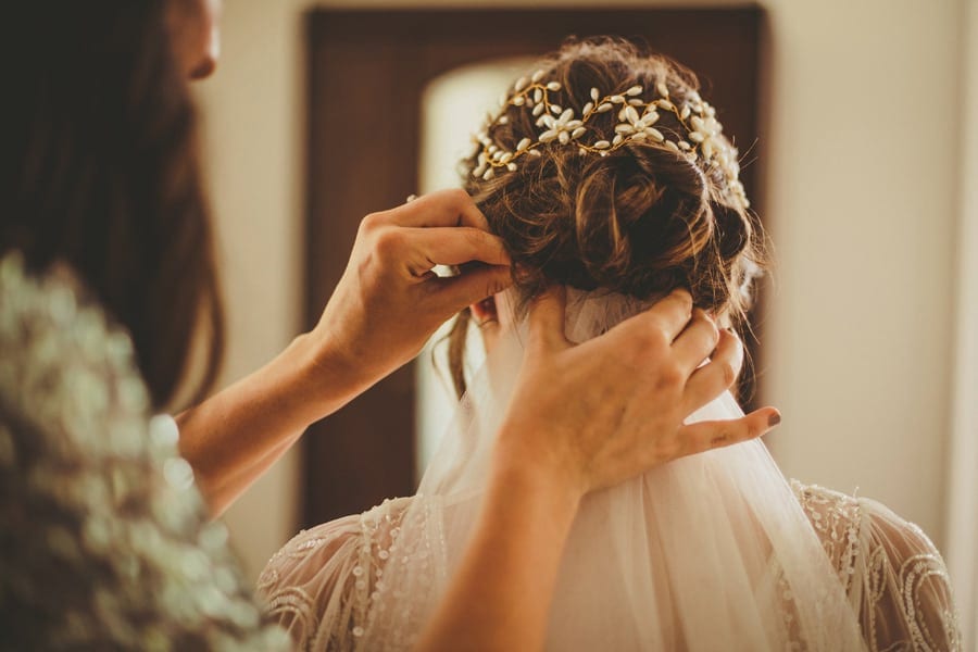 A bridesmaid places the veil into the back of the brides hair
