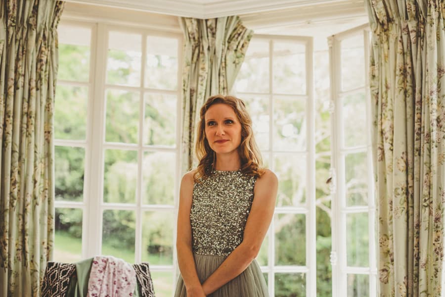 A bridesmaid smiles as she watches the bride getting ready
