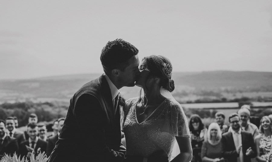 The bride and groom kiss each other during the outdoor ceremony