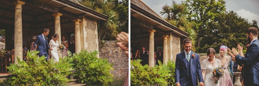 The bride and groom walk away from the outdoor ceremony as the wedding guests clap their hands