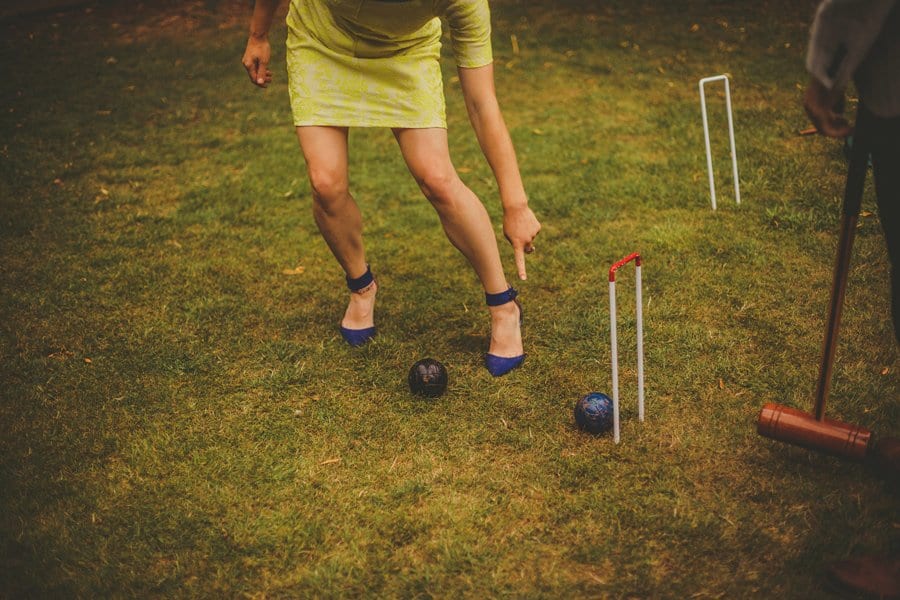 A lady points at a croquet ball as a man stands and looks on the lawn at Barley Wood house