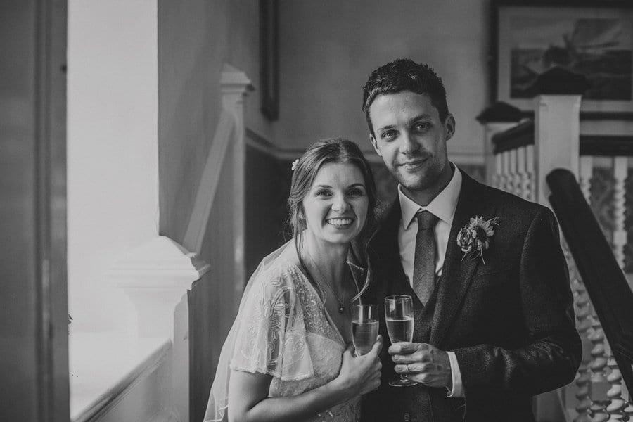 The bride and groom pose for a photograph at the top of the main staircase at Barley Wood house