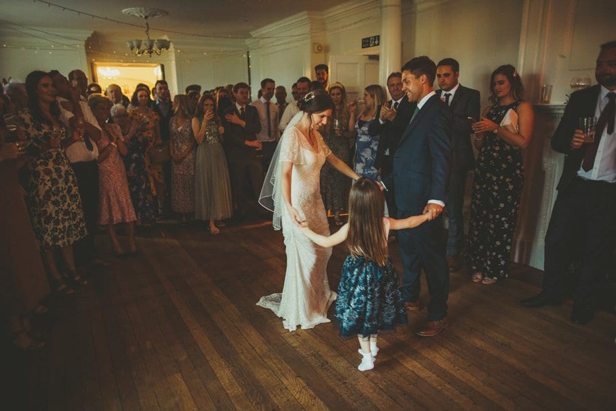 The bride and groom dance with the flower girl