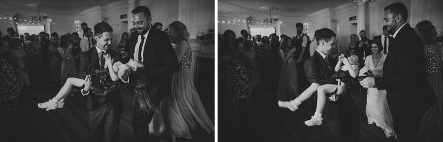 The groom holds the flower girl in his arms on the dance floor
