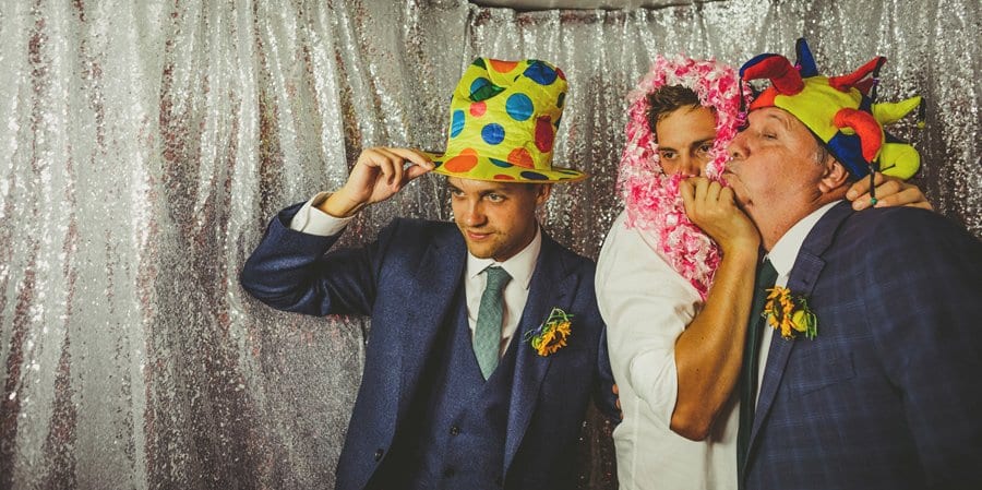 The groom and his family put hats on and pose for photographs in the photo booth
