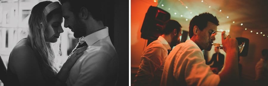 A lady places her head onto the forehead of another man and a wedding guest drinks alcohol from a glass on the dance floor at Barley Wood house