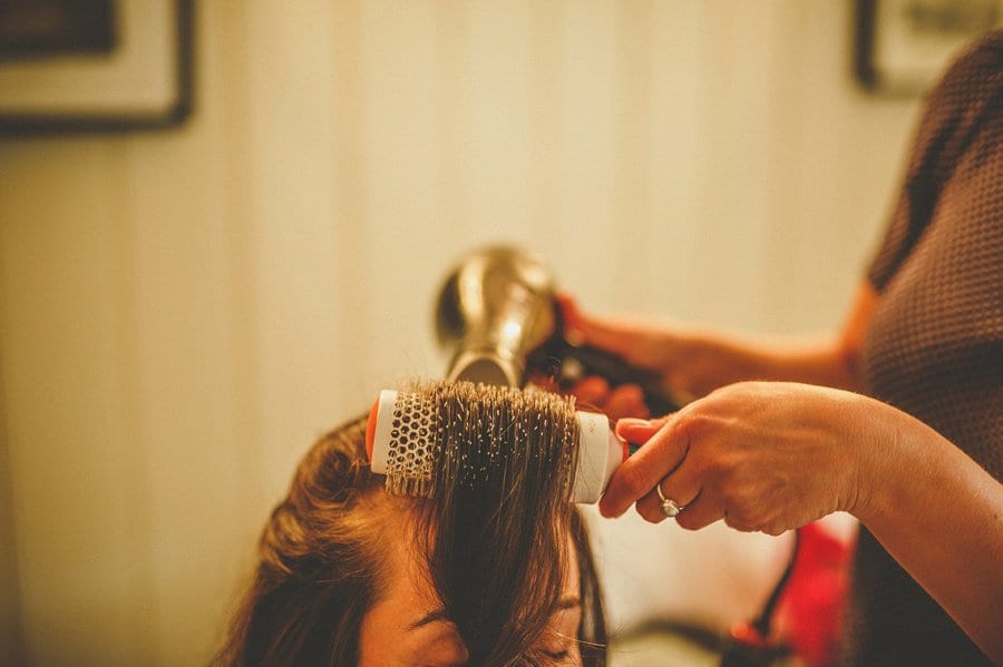 A hairdresser curls the bridesmaids hair with her comb