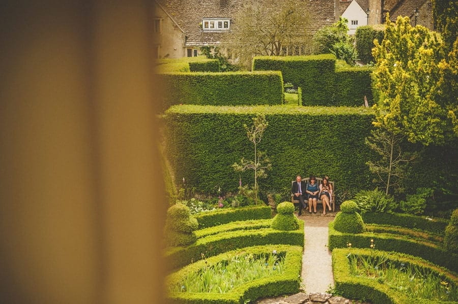Wedding guests sitting on a bench in Abbey House Gardens