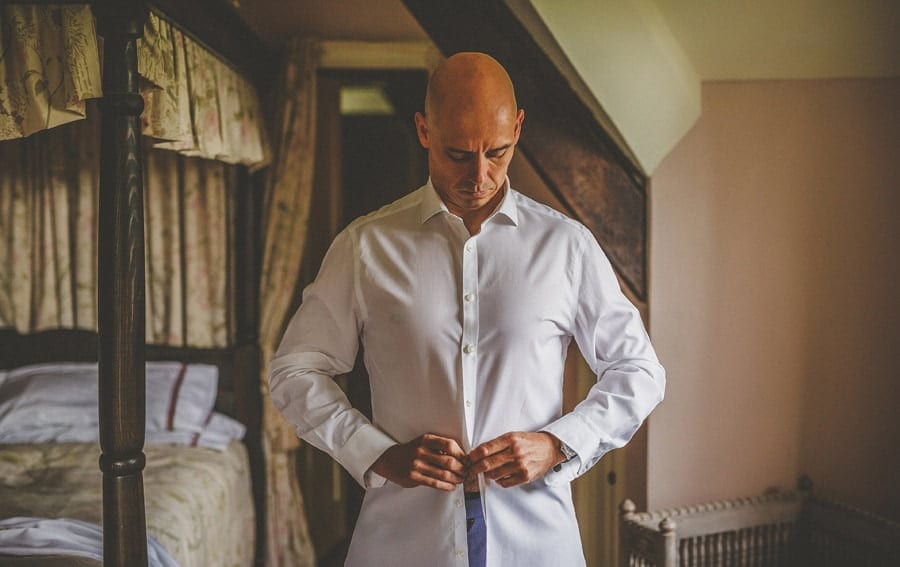 The groom fastens a button on his shirt