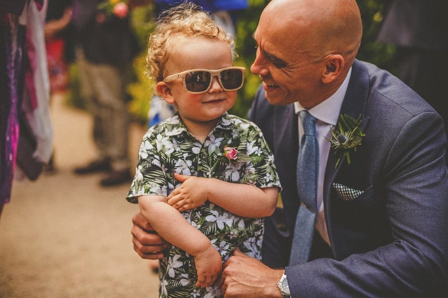 The groom smiles at his son wearing sunglasses