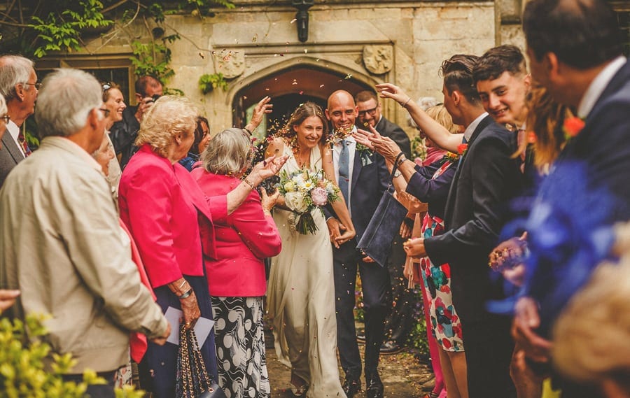 Wedding guests throw confetti over the bride and groom at Abbey house Gardens