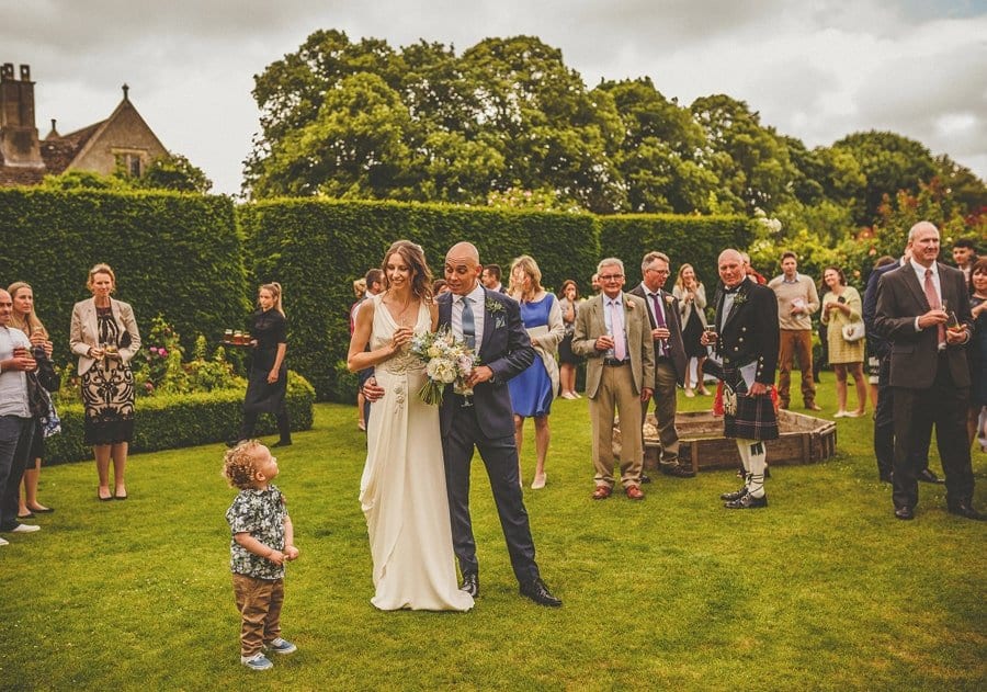 The bride and groom listen to their son in the gardens at Abbey House