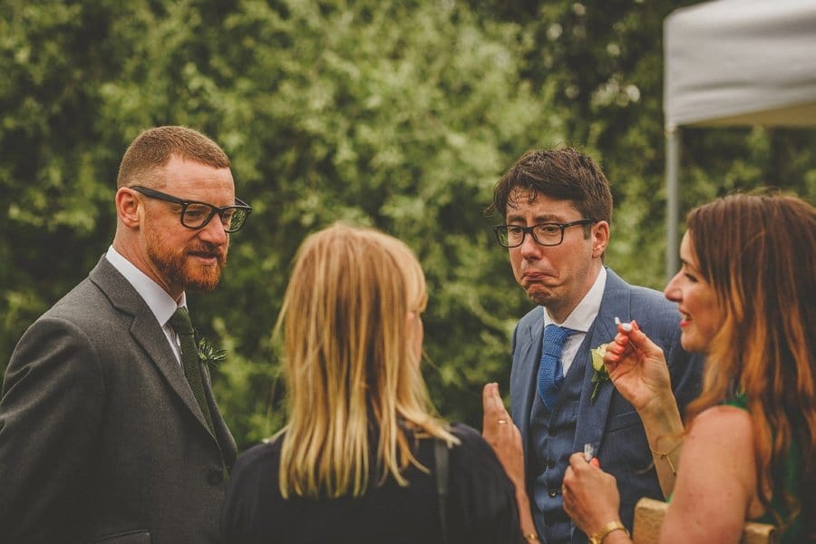 A wedding guest pulls a face as he listens to another wedding guest