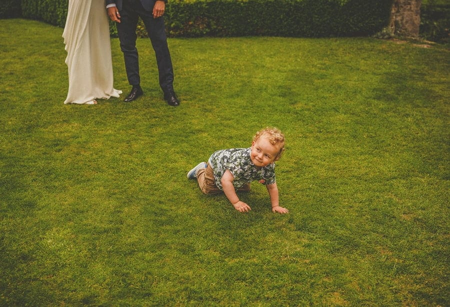 The bride and grooms son crawls along the grass in the gardens at Abbey House