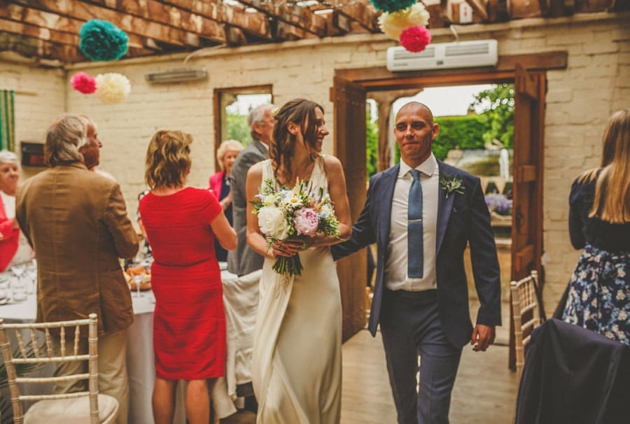 The bride and groom enter the room and wedding guests stand and clap
