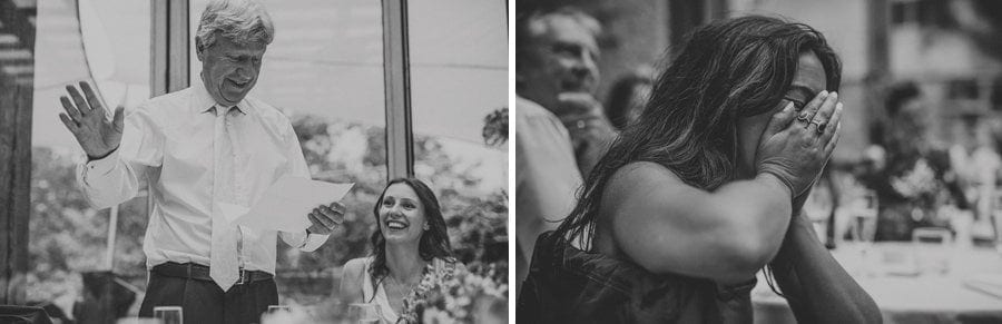 A wedding guest holds her hands in her face and laughs as the brides father delivers his speech