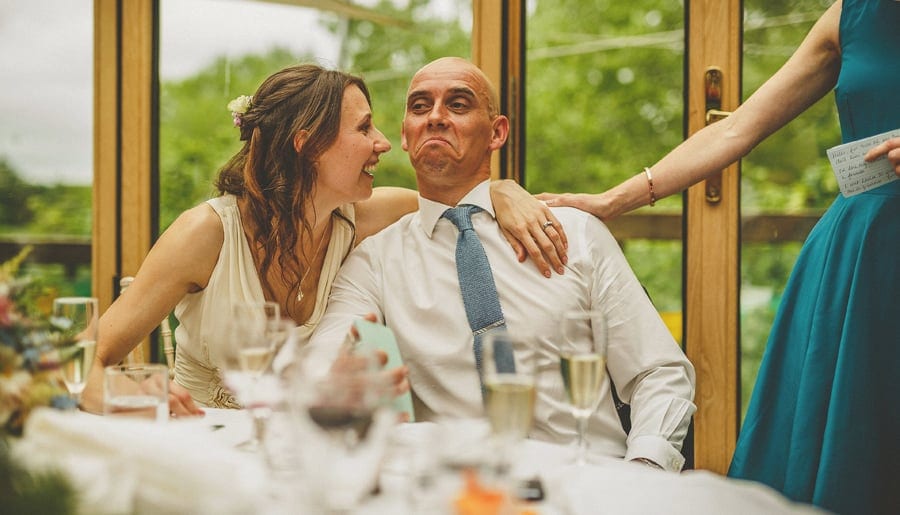 The bride places her arm around her husband and laughs