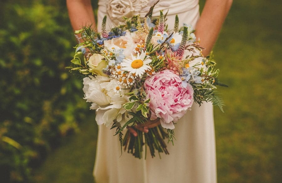 The bride holds her flower bouquet with both hands
