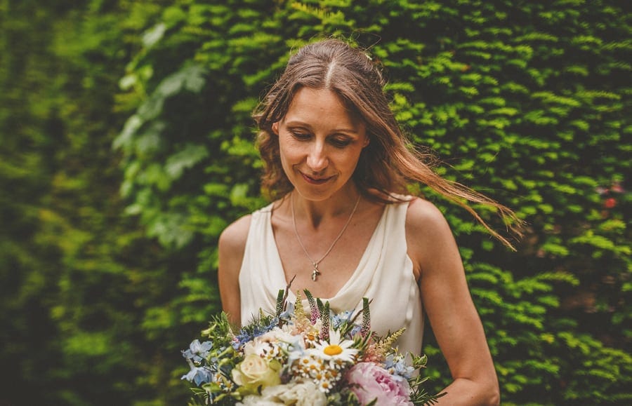 The bride looks down on the floor and holds her wedding bouquet
