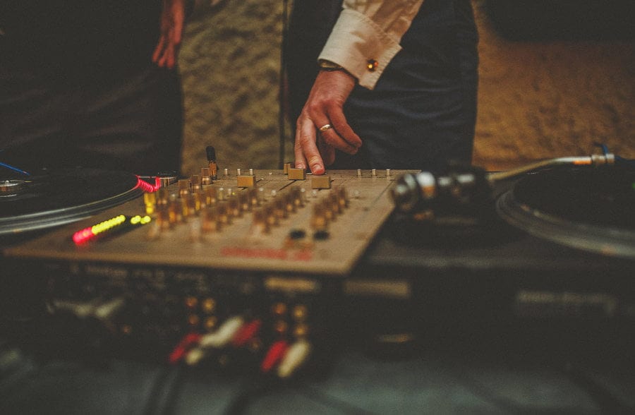 The DJ places his fingers on the mixing desk