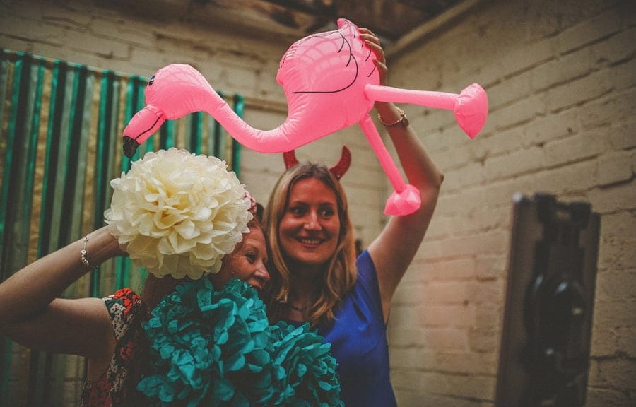 Two ladies hold up an inflatable pink flamingo and pose for a photograph in the photo booth