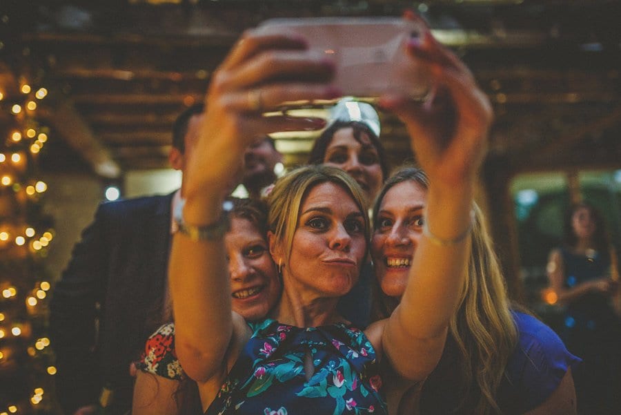 A lady holds up a mobile phone and takes a photograph of herself and her friends on the dancefloor