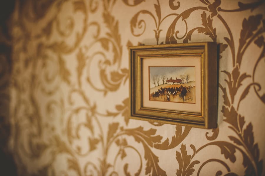 A framed oil painting hangs from a wall in a cottage