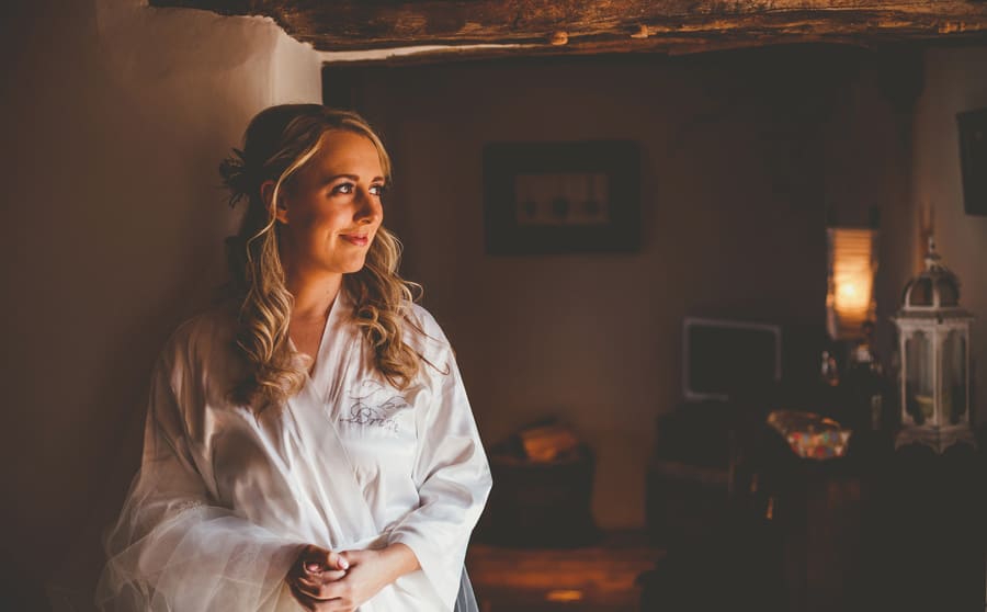 The bride poses for a photograph as she looks outside into the front garden of the kitchen