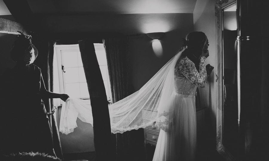 The bridesmaid puts on earrings as she looks in the mirror in the bedroom