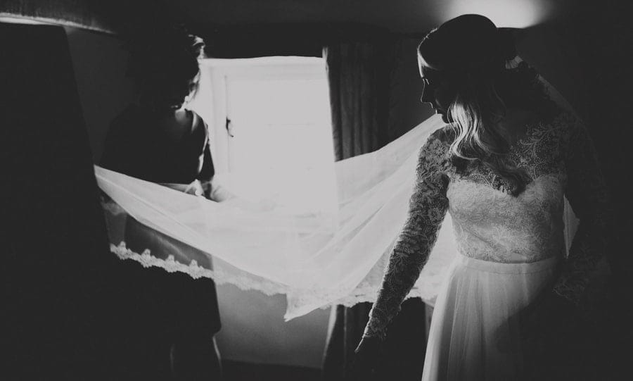 The bridesmaids hold the brides veil in their hands as the bride watches