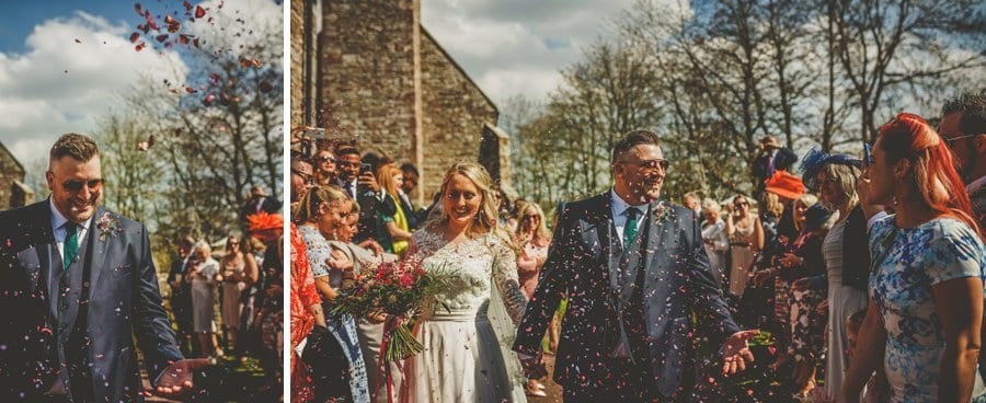 The bride and groom walk out of the church and are showered in confetti