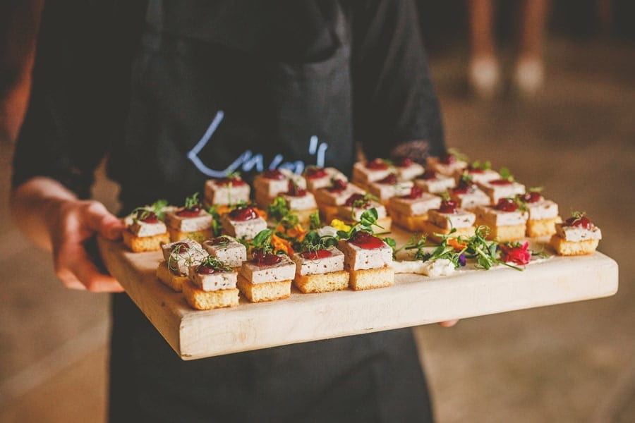 A member of staff from Eden Barn holds a wooden board of canapes