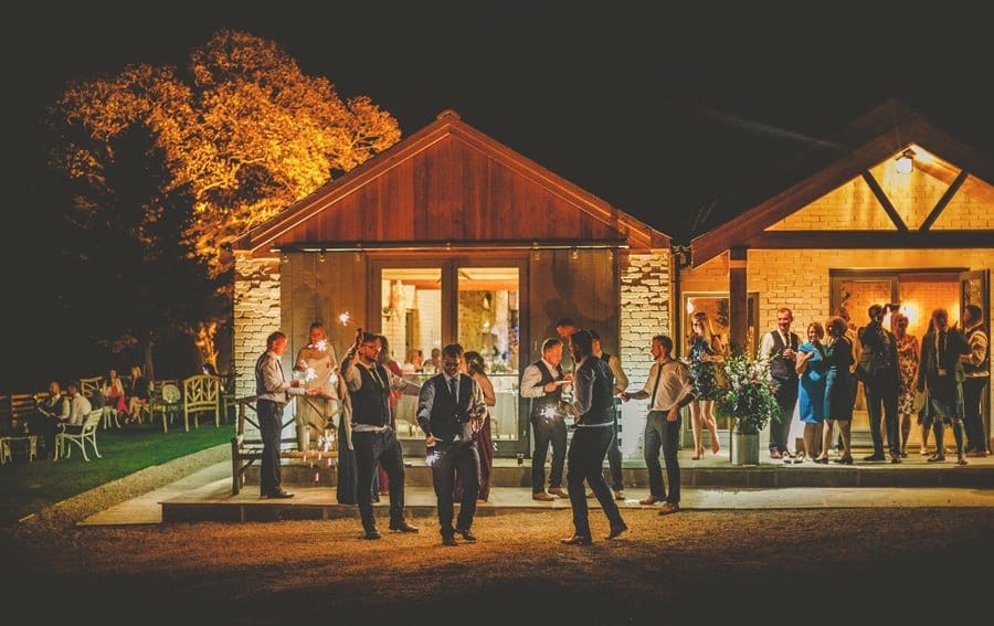 Wedding guests light sparklers outside Eden Barn in the evening