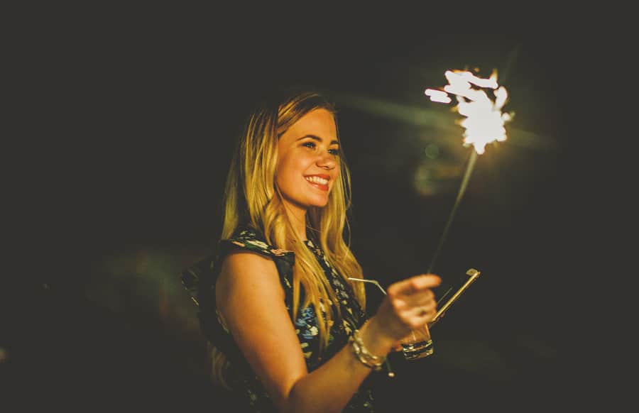 A wedding guest waves a sparkler in the air outside Eden Barn