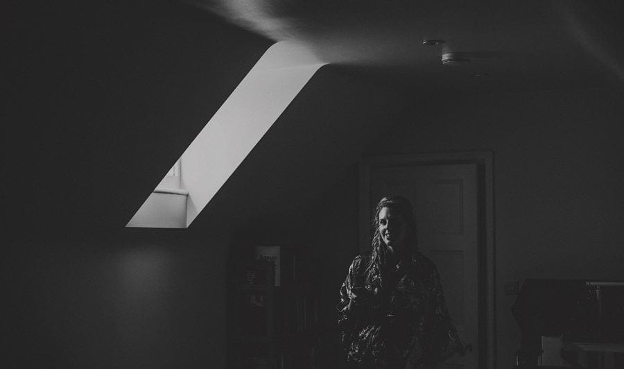 A bridesmaid stands and poses for a photograph in one of the bedrooms of the bride's house